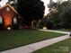 Well-maintained lawn with a brick house, a fountain, and mature trees in the background at 10011 Spring Park Dr, Charlotte, NC 28269