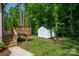 Backyard view featuring a small deck with stairs and a white storage shed surrounded by lush greenery at 1012 W Carroll St, Cherryville, NC 28021