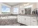 Bright bathroom featuring a soaking tub with tile surround and a vanity with granite countertop at 1098 Matchstick Sw Pl, Concord, NC 28025