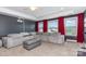 Bright bonus room with plush sectional sofa, projector, and large windows with red drapes at 1098 Matchstick Sw Pl, Concord, NC 28025