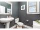 Stylish half bath with a pedestal sink, decorative mirror, and modern fixtures at 1098 Matchstick Sw Pl, Concord, NC 28025