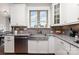 Close up on a well lit kitchen with stainless steel appliances, granite counters, white cabinetry and tile backsplash at 1098 Matchstick Sw Pl, Concord, NC 28025