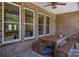 Covered patio showcasing a wooden dining table and bench seating, perfect for enjoying outdoor meals with brick columns at 115 Woodward Way, Iron Station, NC 28080
