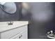 A half bathroom features a stylish dark gray wall, a mirror, and a sink with a white vanity cabinet at 13932 Queens Harbor Rd, Charlotte, NC 28278
