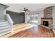 Bright living room featuring hardwood floors, stone fireplace, and a ceiling fan at 13932 Queens Harbor Rd, Charlotte, NC 28278