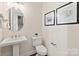 The well-appointed powder room features a pedestal sink, round mirror, and modern fixtures at 149 Glenn Dr, Mooresville, NC 28115