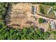 An aerial view of the lot for sale showcasing a home, greenhouse, and surrounding mature trees at 159 Old Home Pl, China Grove, NC 28023