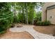 Stone fire pit area with pavers, a built-in bench, and lush landscaping for outdoor entertaining at 1654 Scotch Pine Ln, Fort Mill, SC 29708