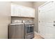 Functional laundry room featuring modern washer and dryer units, white cabinetry, and a utility sink at 1654 Scotch Pine Ln, Fort Mill, SC 29708