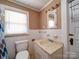 Cozy bathroom with toilet, vanity, mirror, and window at 225 N Main St, Mount Pleasant, NC 28124
