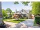 View of the home with long driveway, mature landscaping, brick exterior, chimney, and a detached garage at 2304 Commonwealth Ave, Charlotte, NC 28205