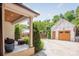 Covered outdoor area with stone flooring, wicker seating, and a view of a detached garage with a wooden door at 2304 Commonwealth Ave, Charlotte, NC 28205