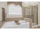Main bathroom featuring soaking tub, tiled shower, and a large window with wood blinds at 2817 Bevis Ln, Waxhaw, NC 28173