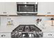 Close-up of stainless gas cooktop with white tile backsplash and quartz countertop at 329 Secretariat Dr, Iron Station, NC 28080