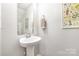 Cozy powder room featuring pedestal sink, decorative mirror, and botanical wall art at 4009 Stoneygreen Ln, Charlotte, NC 28215