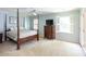 Spacious bedroom featuring a four-poster bed, neutral carpet, light blue walls, and natural light from two windows at 4234 Woodglen Ln, Charlotte, NC 28226