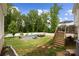 Backyard pool area with lounge chairs and deck with table and chairs with green lawn and trees at 5384 Gatsby Cir, Rock Hill, SC 29732