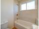 Bright bathroom with a tub and shower combination, window, and neutral colored walls at 55 Ranlo Ave, Gastonia, NC 28054