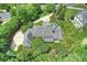 An elegant home boasts meticulously maintained grounds, a winding driveway, and architectural details surrounded by mature trees at 5701 Challisford Ln, Charlotte, NC 28226