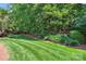 Beautifully landscaped backyard with lush green lawn, mature trees, and vibrant flowerbeds at 5701 Challisford Ln, Charlotte, NC 28226