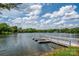 Picturesque lake view with a white dock, surrounded by lush greenery and blue skies at 5701 Challisford Ln, Charlotte, NC 28226