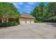 Brick home showcasing a spacious three-car garage with ample parking and mature landscaping at 5701 Challisford Ln, Charlotte, NC 28226