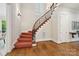 Grand staircase with hardwood floors, red patterned carpet, and decorative iron railing at 5701 Challisford Ln, Charlotte, NC 28226