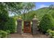 Elegant stone gate with a wooden door featuring a decorative horse emblem, nestled among lush greenery at 6164 Dwayne Starnes Dr, Hickory, NC 28602