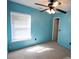 Bright bedroom featuring blue walls, a ceiling fan, neutral carpet, and a window with blinds at 6614 Wicked Oak Ln, Charlotte, NC 28216