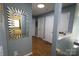 Hallway with blue walls, wood floors, multiple doors, and a decorative mirror at 6614 Wicked Oak Ln, Charlotte, NC 28216