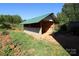 Backyard shed with open walls, green grass, and surrounded by trees at 6614 Wicked Oak Ln, Charlotte, NC 28216