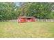 Red barn on a lush green lawn enclosed by a white fence, adding rural charm at 6910 Birdsong Ln, Waxhaw, NC 28173