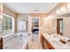 Bright bathroom boasts double sinks, separate tub, and shower, with view to bedroom beyond at 6910 Birdsong Ln, Waxhaw, NC 28173