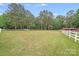 Expansive green yard with white fencing and trees, featuring a charming red outbuilding at 6910 Birdsong Ln, Waxhaw, NC 28173