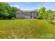 Expansive backyard view of a brick home with a deck, lush green lawn, and a gentle slope at 7365 Gabriel St, Sherrills Ford, NC 28673