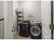 Laundry room featuring a dark washer and dryer, white storage bins, and neutral tile flooring at 7365 Gabriel St, Sherrills Ford, NC 28673