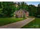Beautiful two-story brick home with a long driveway, lush lawn, and mature trees offering privacy and curb appeal at 801 Hidden Pond Ln, Waxhaw, NC 28173