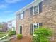Brick townhome features black shutters and is complemented by lush greenery for an inviting facade at 8049 Regent Park Ln, Charlotte, NC 28210