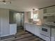 The kitchen features white cabinets, modern appliances, gray walls, and new wood-style vinyl flooring at 874 Old Home Place Way, Lincolnton, NC 28092