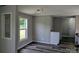 A well-lit living room with wood-style vinyl flooring, modern lighting, gray walls, and natural light from a window at 874 Old Home Place Way, Lincolnton, NC 28092
