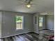 A bright living room featuring gray walls, new wood-style vinyl flooring, and natural light from two windows at 874 Old Home Place Way, Lincolnton, NC 28092