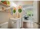 Neutral bathroom with round mirror, floral wall decor, and view to study or office space with desk and natural lighting at 9003 Smokey Hill Ln, Fort Mill, SC 29707