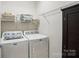 Laundry room featuring front loading washer and dryer, storage shelves, dark brown linen cabinet, and white walls at 9003 Smokey Hill Ln, Fort Mill, SC 29707