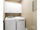 Bright laundry room with white washer, dryer, and upper cabinets for storage at 9735 Wheatfield Rd, Charlotte, NC 28277