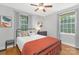 Inviting bedroom with two windows, hardwood floors, ceiling fan, and a comfortable bed with colorful pillows at 1100 Mona Dr, Charlotte, NC 28206