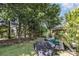 Lush backyard featuring mature trees, a swing, a hammock, patio area, and a covered grill at 11807 Hawick Valley Ln, Charlotte, NC 28277