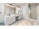 Bright bathroom featuring double sink vanity with white cabinets, large mirrors, and tiled flooring at 11807 Hawick Valley Ln, Charlotte, NC 28277