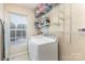 Functional laundry room with white washer and dryer, shelving, and a window for natural light at 11807 Hawick Valley Ln, Charlotte, NC 28277