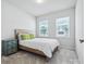 Bright bedroom features two windows, carpet flooring, and a wooden bed frame with a white comforter at 119 Berkeley Ave # A, Mooresville, NC 28117