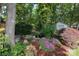 Landscaped backyard with lush garden, flowering plants, and decorative stone accents at 1261 Hawthorne Dr, Indian Trail, NC 28079